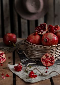 pomegranates in a wicker basket on top of a wooden table