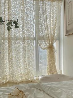 a white bed sitting next to a window covered in curtains