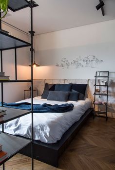 a bed sitting in the middle of a room next to a lamp and bookshelf