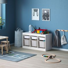 a child's room with blue walls, toys and storage bins on the floor