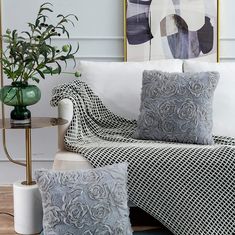 a white couch with two pillows on top of it and a green plant in the corner