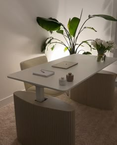 a white table with two chairs and a laptop on it in front of a potted plant