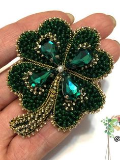 a hand holding a green flower broochle