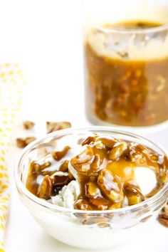 a glass bowl filled with ice cream and caramel toppings next to a jar of syrup