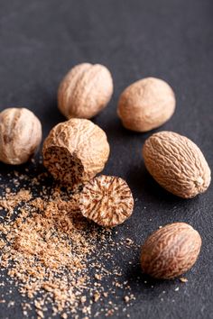 nuts are scattered on a black surface with some brown sugar in the middle and one nut is half eaten