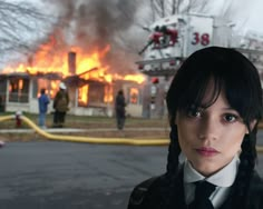 a woman wearing a suit and tie standing in front of a fire that is burning