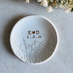 a white plate with the word kod on it next to some flowers and leaves