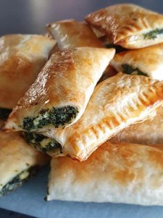 several pastries piled on top of each other in a pile with spinach and cheese