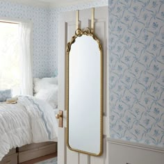 a mirror hanging on the wall next to a bed in a room with blue and white walls