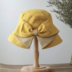 a yellow hat with a big bow on it's head sitting on a wooden stand