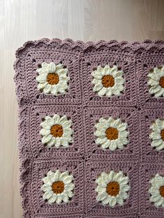 a crocheted blanket with white and brown flowers