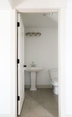 an open door leading to a bathroom with a sink and toilet in it's center