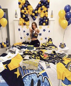 a woman sitting on top of a bed surrounded by yellow and blue balloons