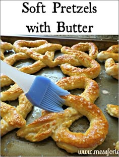 soft pretzels with butter on a baking sheet being brushed by a spatula