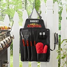 an oven mitt hanging on the side of a white fence with utensils in it