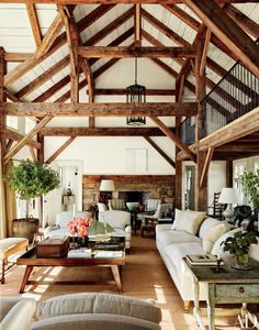 a living room filled with lots of furniture and wooden beams on the ceiling above it