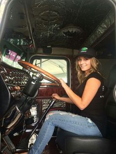 a woman sitting in the driver's seat of a truck holding a steering wheel