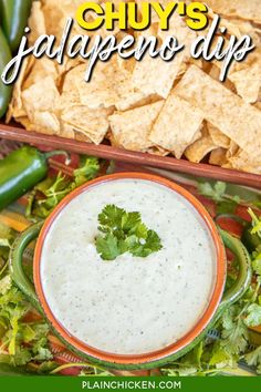 a bowl of guacamole dip surrounded by tortilla chips and jalapenos