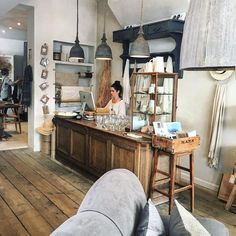 a woman sitting at a counter in a room with lots of furniture and decor on the walls