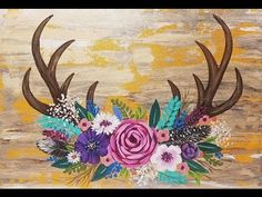 a painting with antlers and flowers on it's side, in front of a wooden background