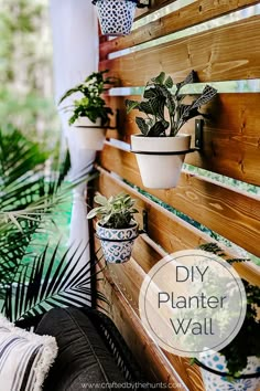 several potted plants are hanging on the side of a wooden wall next to a bench