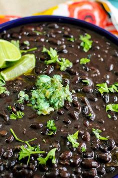 a blue bowl filled with black beans and guacamole garnished with cilantro