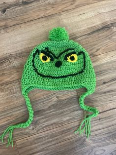 a green crocheted hat with yellow eyes and an angry grin on the front