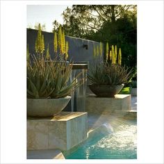 two large planters sitting next to a pool with water running down it's sides