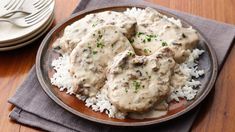 a plate filled with rice and meat covered in gravy on top of a wooden table