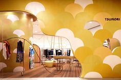 a store display with an artistic wallpaper and circular mirrors on the walls, as well as clothing racks