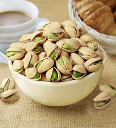 pistachio nuts in a bowl next to some croissants