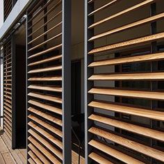 wooden slats on the side of a building in front of a window with blinds