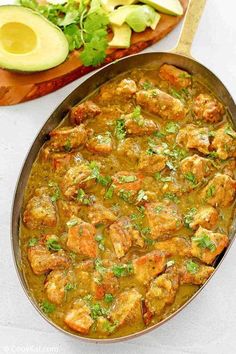 a pan filled with meat and vegetables next to an avocado