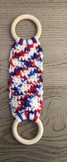 a red, white and blue knitted object with a wooden ring attached to it