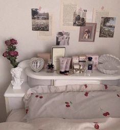 a white bed topped with pink flowers next to a wall covered in pictures and photos