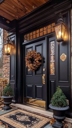 a black front door with two potted plants on the steps and lights above it