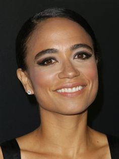 a close up of a person wearing a black dress and smiling at the camera with her eyes closed