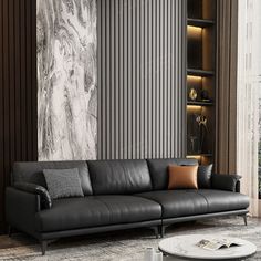 a black leather couch sitting in front of a large painting on the wall next to a coffee table