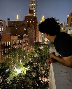 a young man is looking out over the city at night from a high rise building