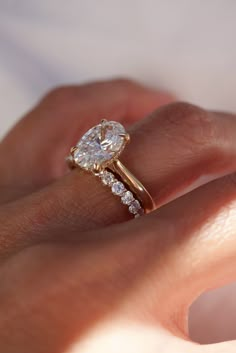 a woman's hand with a diamond ring on top of her finger and an engagement band