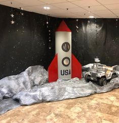 a space shuttle on display in a room with black walls and stars hanging from the ceiling