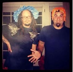 two men standing next to each other with wigs on their heads and one wearing a blue shirt