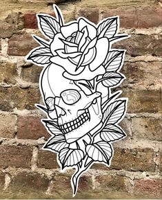 a sticker with a skull and roses on it in front of a brick wall