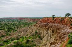 an aerial view of the land and trees in the distance, with many layers of rock on each side