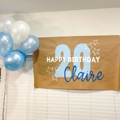 a happy birthday banner hanging on the wall with balloons and streamers in front of it