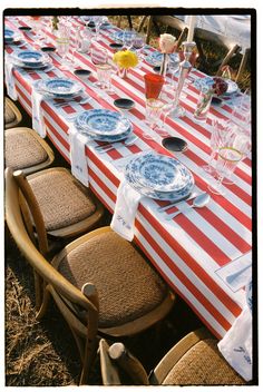 a long table with plates and glasses on it is set up for an outdoor dinner