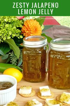 two jars filled with lemon jelly sitting on top of a wooden table next to crackers