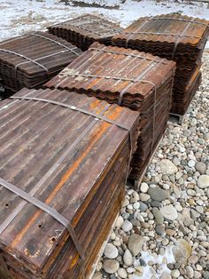 several old rusty metal boxes sitting on top of some rocks and gravel near the water