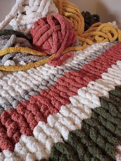 there are many different colors of yarn on the bed sheet that is crocheted