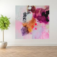 an abstract painting on the wall next to a potted plant in a white room